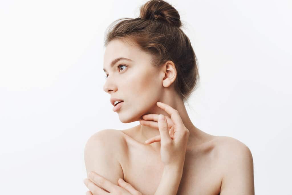 Woman touching her smooth, tight jawline after having a face and neck lift