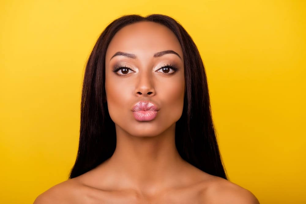 Headshot of a woman pursing her lips to show off her lip filler.