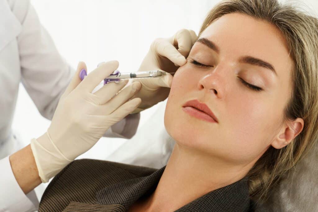 Woman having dermal fillers injected to her cheekbones for hollow undereyes